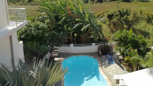 Ein Swimmingpool, umgeben von üppiger Vegetation und mit Blick auf eine entfernte Landschaft.