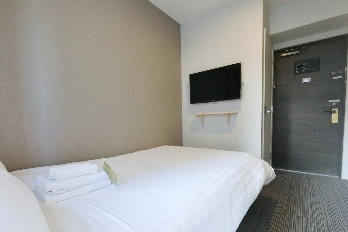 Ein Hotelzimmer mit einem Bett, einem wandmontierten Flachbildfernseher und einer Tür mit Schloss.