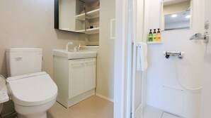 Un baño con inodoro, lavabo, espejo y ducha.