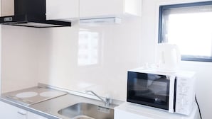 Una cocina moderna con microondas, hervidor y un lavabo de acero inoxidable.