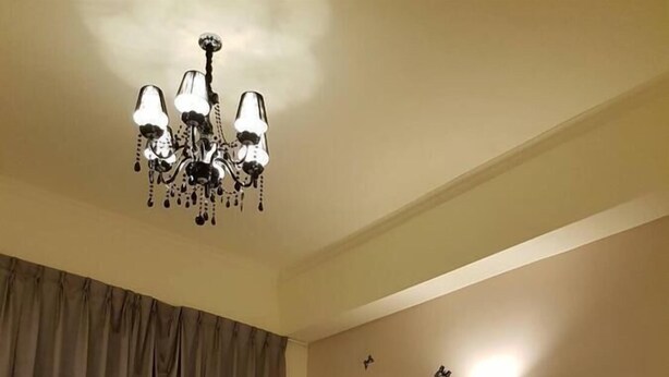 Habitación de hotel con dos camas, un candelabro, una lámpara de pared y un adorno mural.