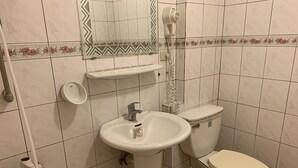 Un baño con lavamanos, inodoro y ducha blancos.