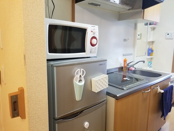 A compact kitchenette with a microwave, a stainless steel refrigerator, and a sink.