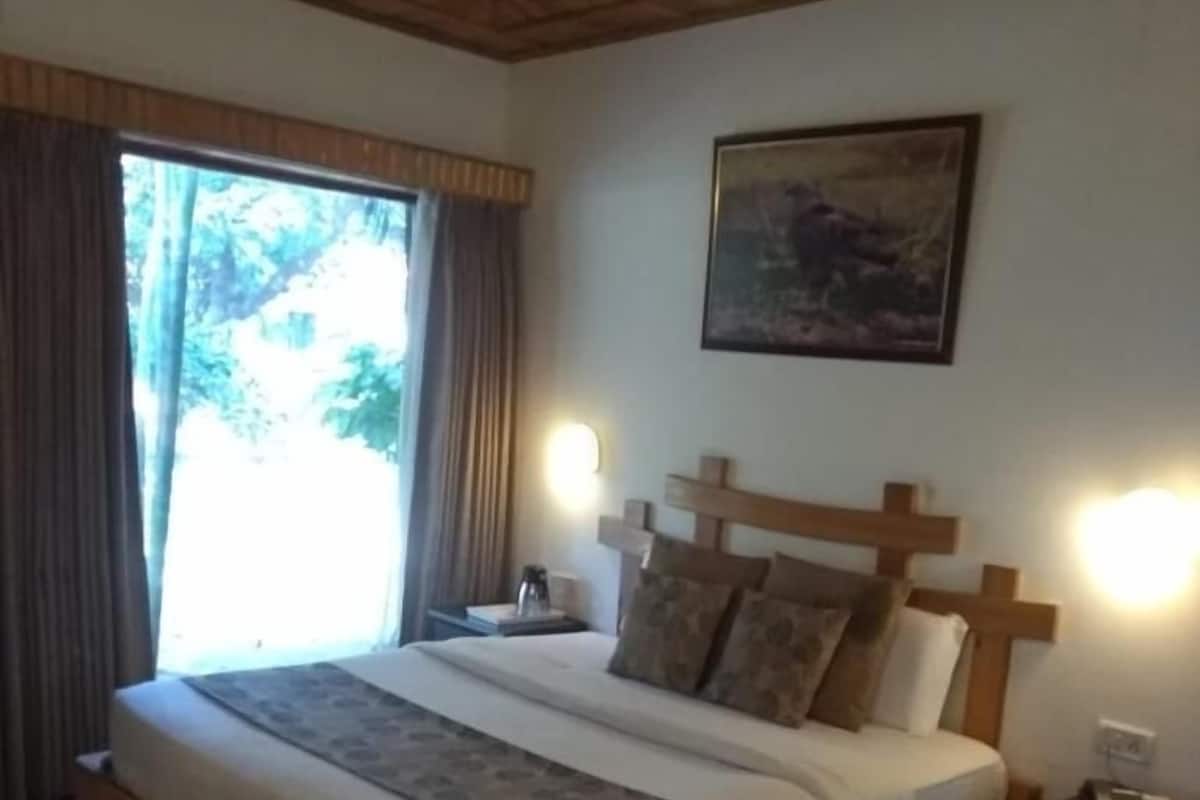Un dormitorio con una cama de madera, una mesita de noche, un cuadro en la pared y una ventana con cortinas.