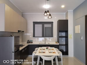 Una cocina moderna con comedor, que incluye un amplio ventanal, un refrigerador y una mesa preparada para cuatro.
