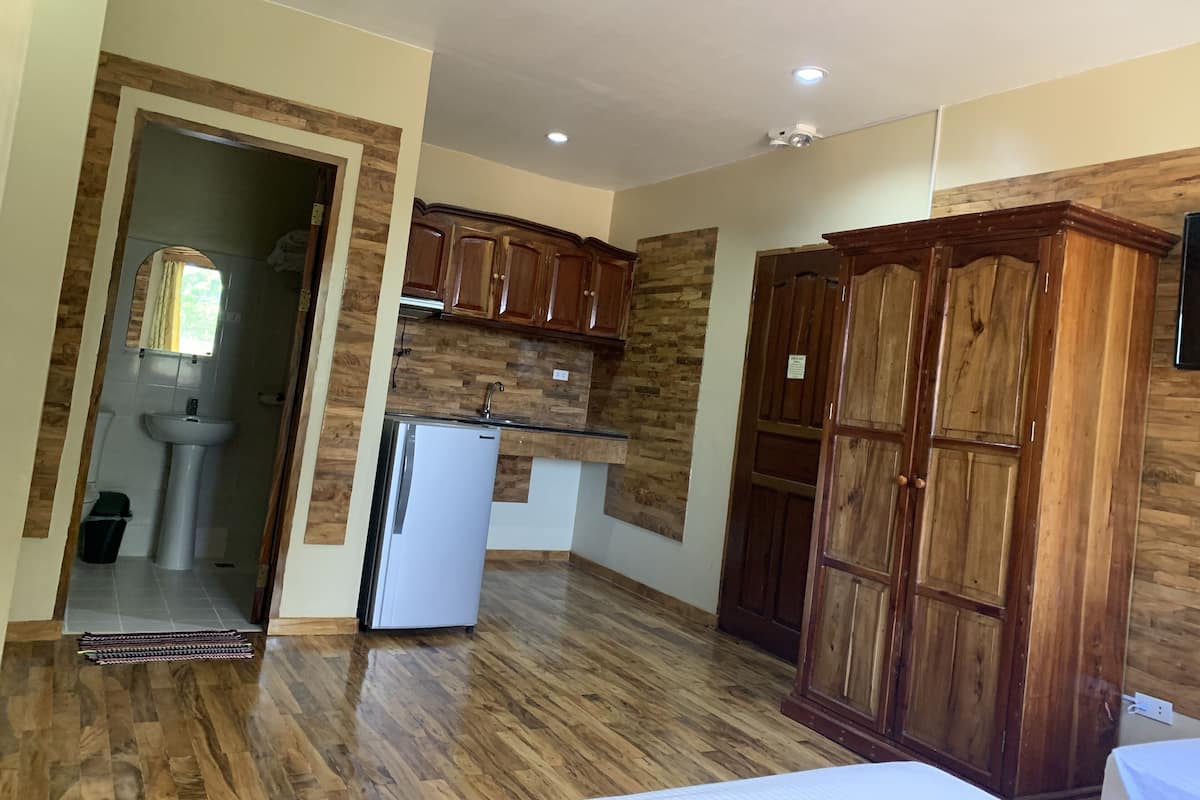 A kitchen with wooden cabinets, a refrigerator, and a sink.