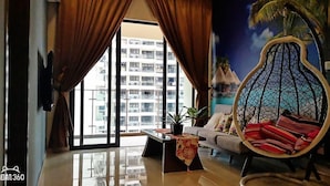 A living room with a large window, a sofa, a hanging chair, and a small table with a plant. - Garden View Suites (Johor Bahru)