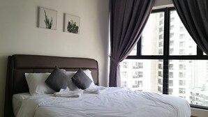 A hotel room with a large bed, dark curtains, and a view of high-rise buildings. - Garden View Suites (Johor Bahru)