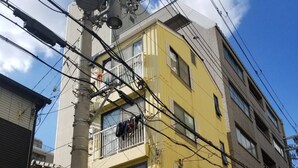 A multi-story building with a yellow facade, a visible storefront with a sign reading "Petal Beauty Salon," and a parked scooter in front. - Petit Asahi 201 (Kobe)