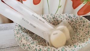 A toiletry bag with a floral pattern, containing a toothbrush, toothpaste, and soap. - Petit Asahi 201 (Kobe)