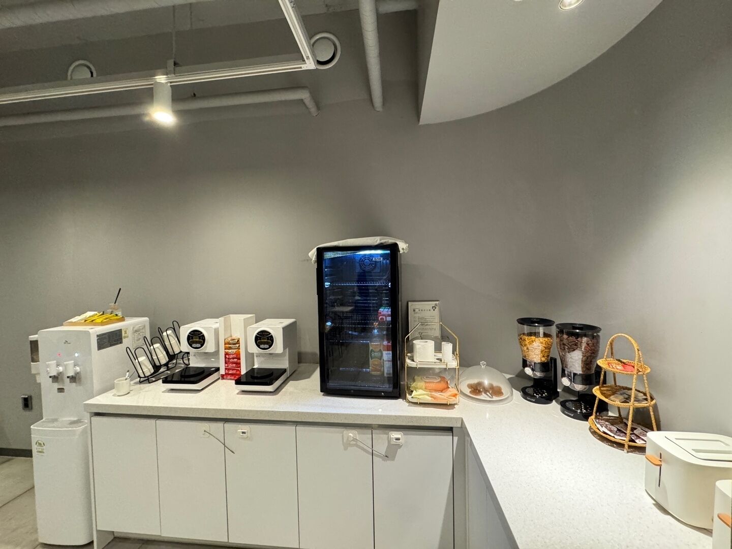 Cozinha moderna com máquina de café, geladeira e diversos recipientes de comida.