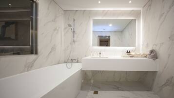 Un baño moderno con una bañera independiente, un espejo grande y un mueble de tocador con artículos de aseo.