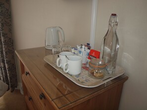 A wooden dresser with a glass top, holding a tray with a coffee maker, two white mugs, a glass jar, and some packets. - Herriot's in Hawes (Hawes)