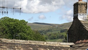 A stone-roofed building with a small skylight and a chimney. - Herriot's in Hawes (Hawes)