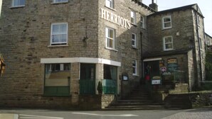 A stone building with a sign reading "HERROOT'S". - Herriot's in Hawes (Hawes)