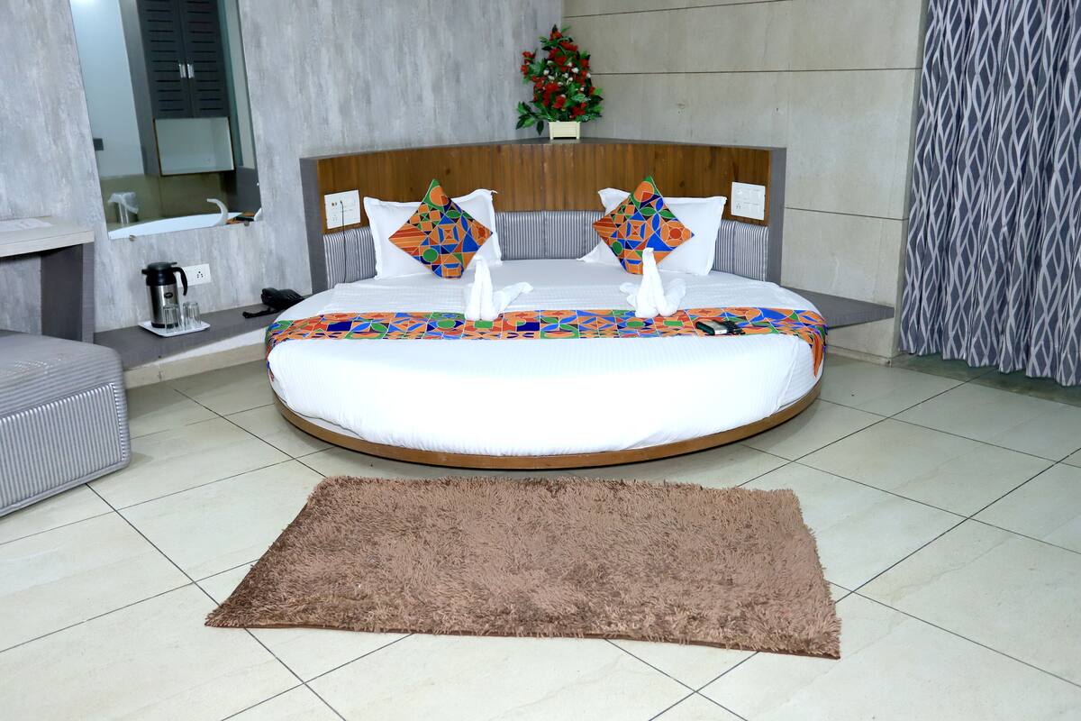 Quarto moderno com cama redonda, tapete fofinho, cabeceira de madeira e uma pequena planta.