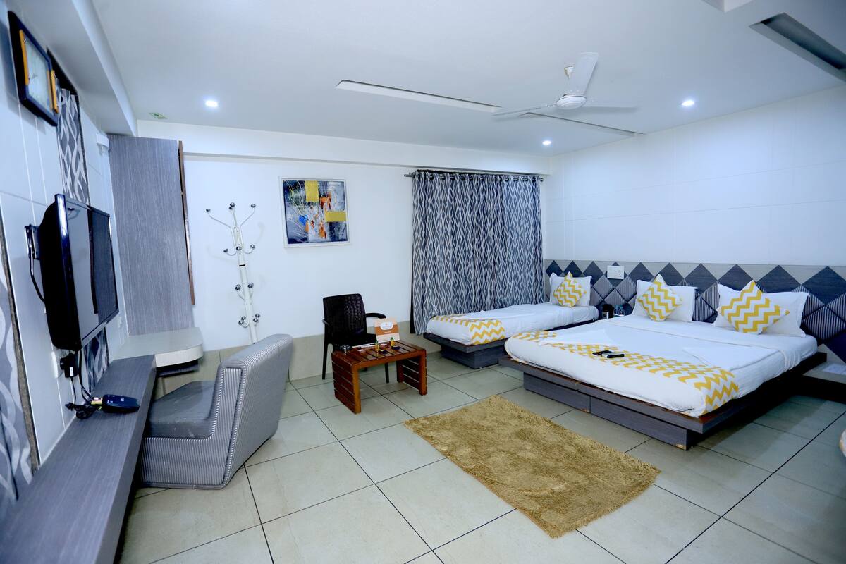 Quarto de hotel moderno com duas camas, uma televisão, uma escrivaninha e uma cadeira.