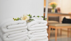 A stack of neatly folded white towels on a chair with a small floral arrangement on top. - Jerry Blossom - Hostel (Seoul)