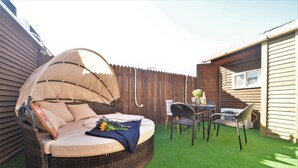 A round wicker sofa with a canopy, a small table with chairs, and a window in a wooden house with a wooden fence. - Jerry Blossom - Hostel (Seoul)