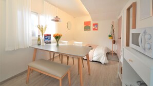 A dining area with a table, chairs, a bench, a vase with flowers, and a television. - Jerry Blossom - Hostel (Seoul)