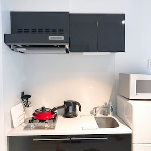 Uma cozinha compacta com fogão, micro-ondas e armários pretos.