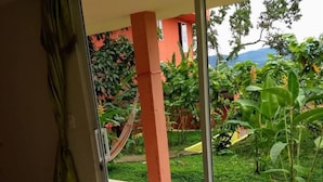A room with a sliding glass door leading to an outdoor area with a tiled floor, a blue mat, and a hammock. - Hostal Tena Ñaui (Tena)