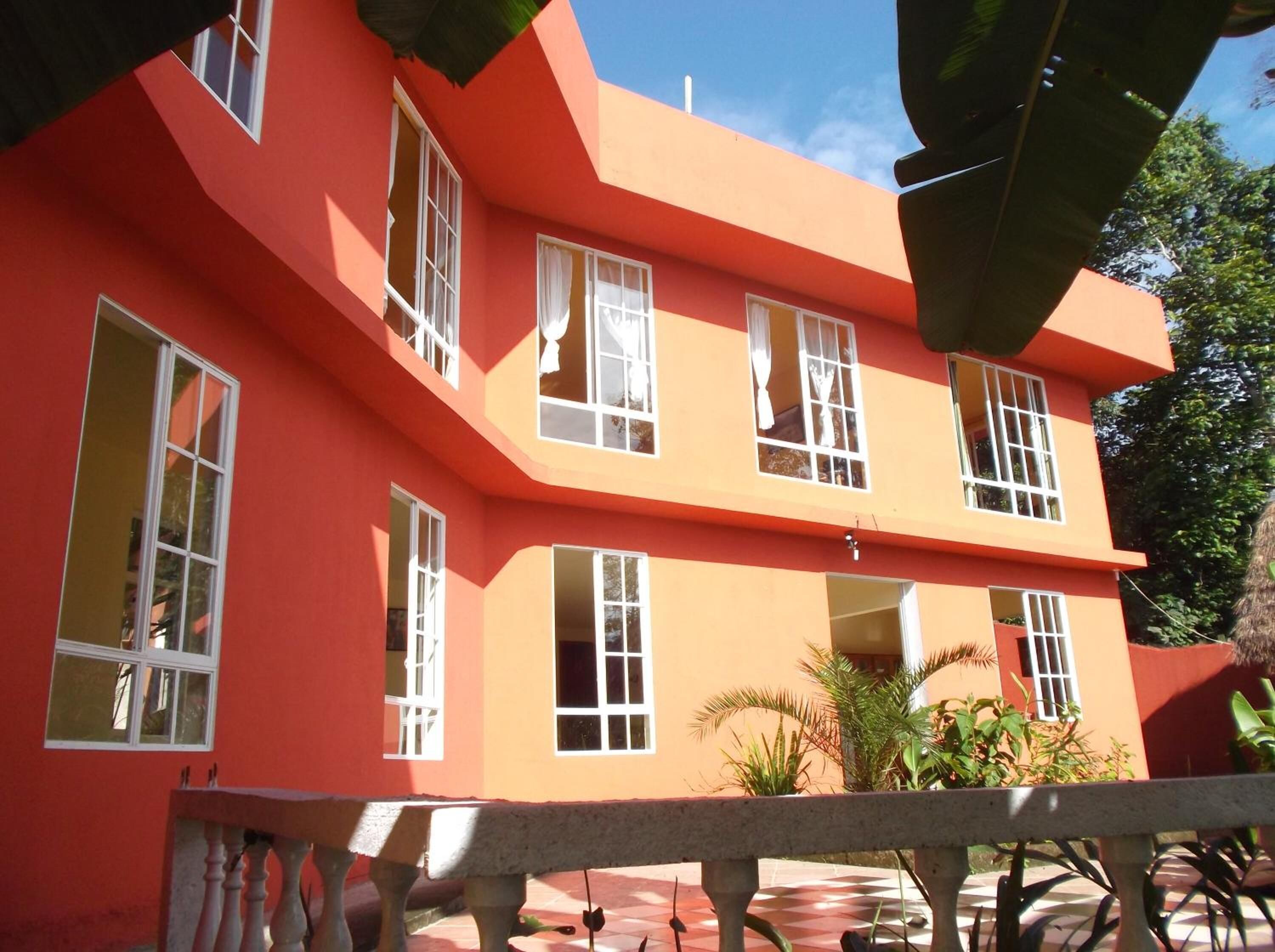 Ein zweistöckiges Gebäude mit roter Fassade und weißen Fensterrahmen.