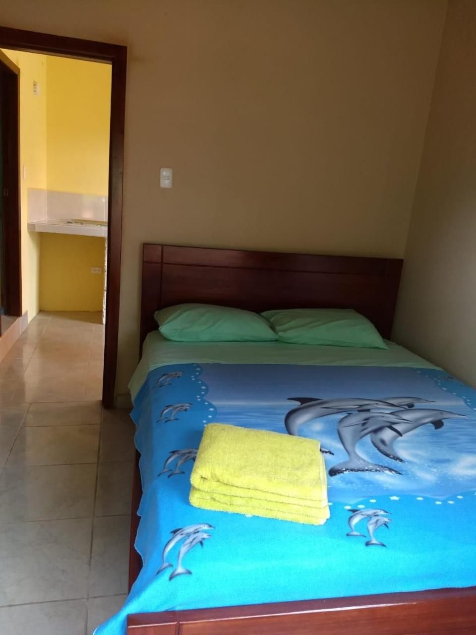 Un dormitorio con una cama, cabecera de madera y una toalla amarilla sobre la cama.