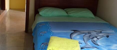 A bedroom with a bed, a wooden headboard, and a yellow towel on the bed.