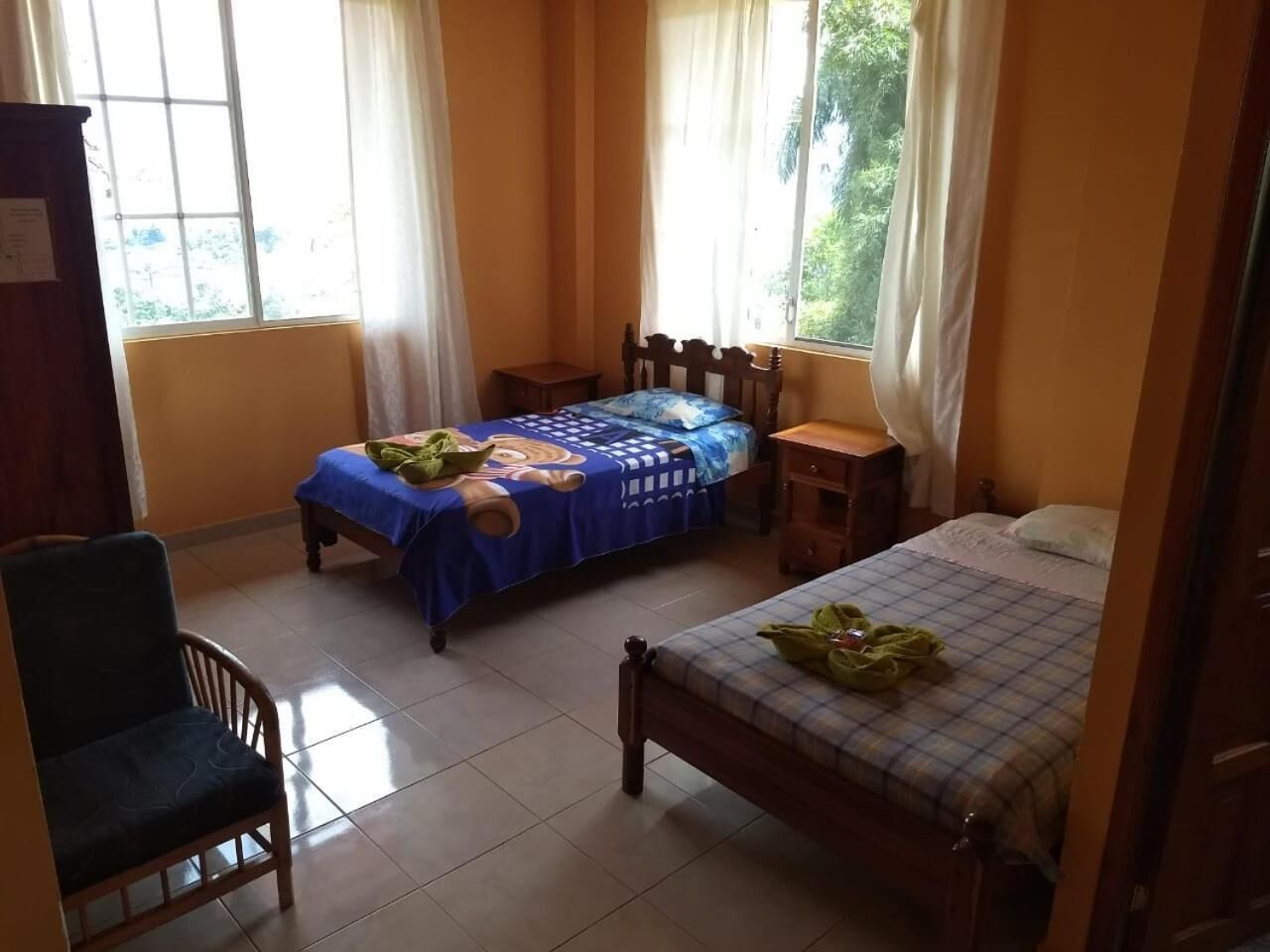 A room with two beds, a chair, and a window.