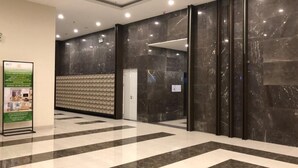 A lobby with a marble floor, a reception desk, and a wall-mounted information board.