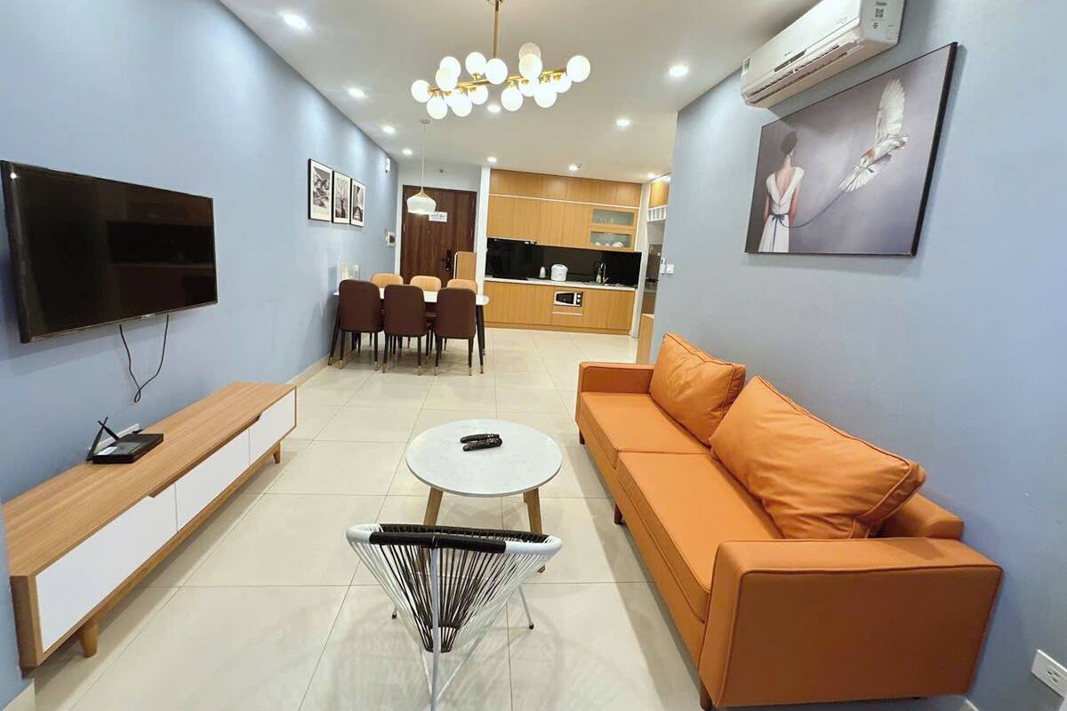 A modern living room with a sofa, TV, and dining area.