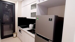 A modern kitchen with white cabinets, a stainless steel refrigerator, and a black countertop.