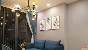 A modern living room with a blue sofa, a round coffee table, and a blue chair. There are three framed botanical prints on the wall.