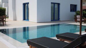 A swimming pool with lounge chairs, a table, and a potted plant. - Blue Moon Villa in Kolympia (RHODES)