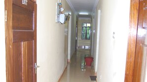A hallway with an exit door, a light fixture, and a red bucket on the floor.