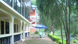 A covered outdoor area with a brick pathway, a blue umbrella, and a seating area with chairs.