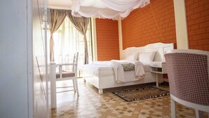 A bedroom with a white bed, a red brick wall, and a patterned floor.