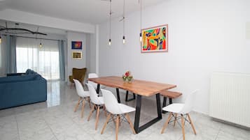 Een moderne eetruimte met een houten tafel, witte stoelen en een kleurrijk abstract schilderij aan de muur.
