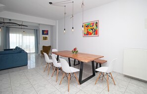 Un comedor moderno con una mesa de madera, sillas blancas y un cuadro abstracto y colorido en la pared.