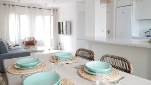 Een moderne eetruimte met een houten tafel voor vier personen, omringd door rieten stoelen.