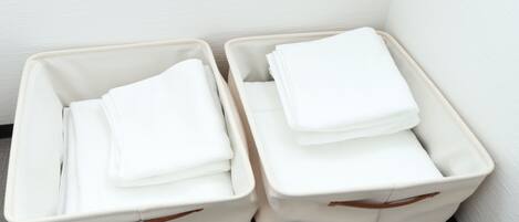 Two white storage bins with handles, stacked with folded white towels.
