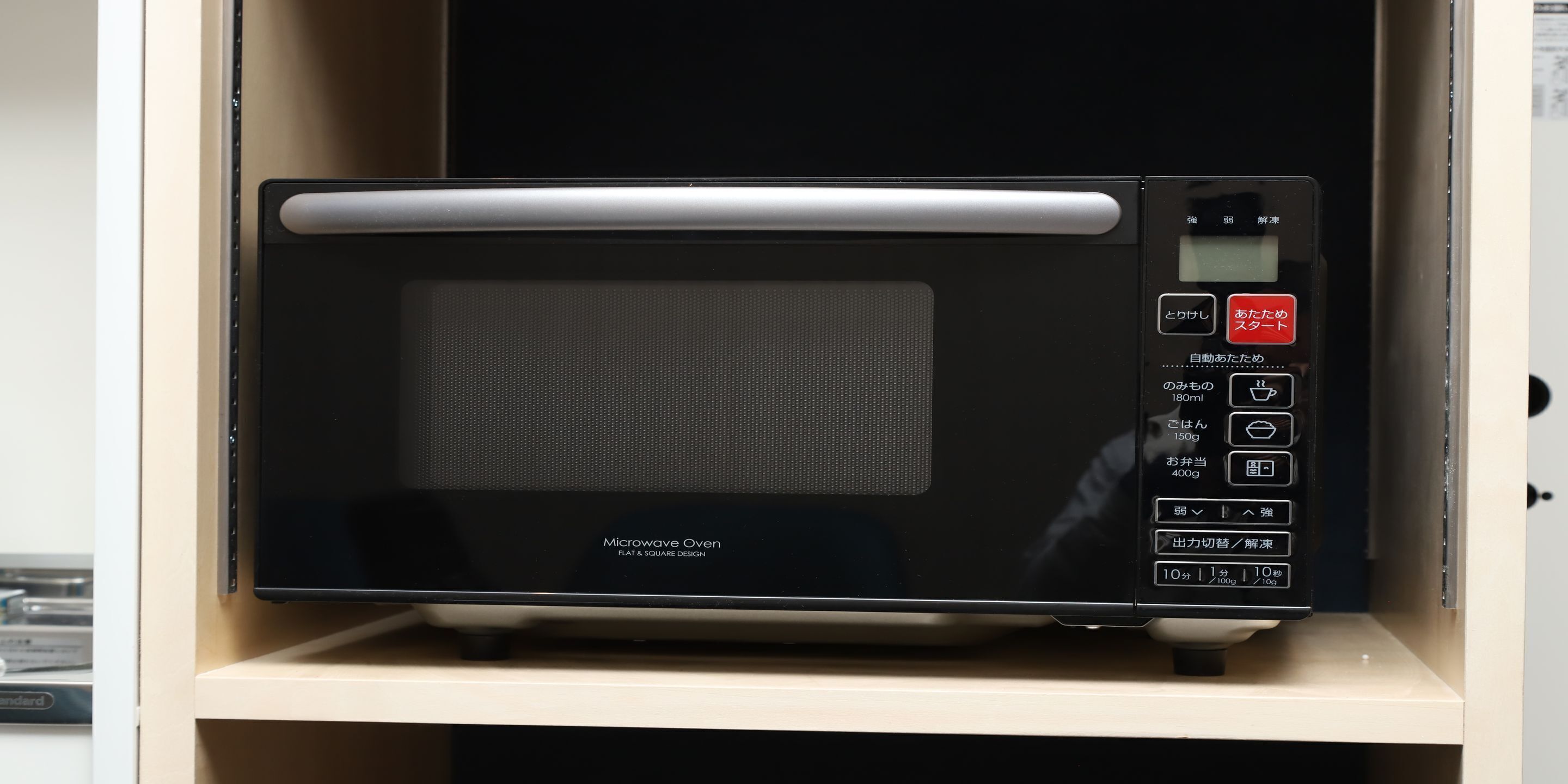 Eine Mikrowelle mit flachem, eckigem Design, einem digitalen Display und verschiedenen Bedienelementen.
