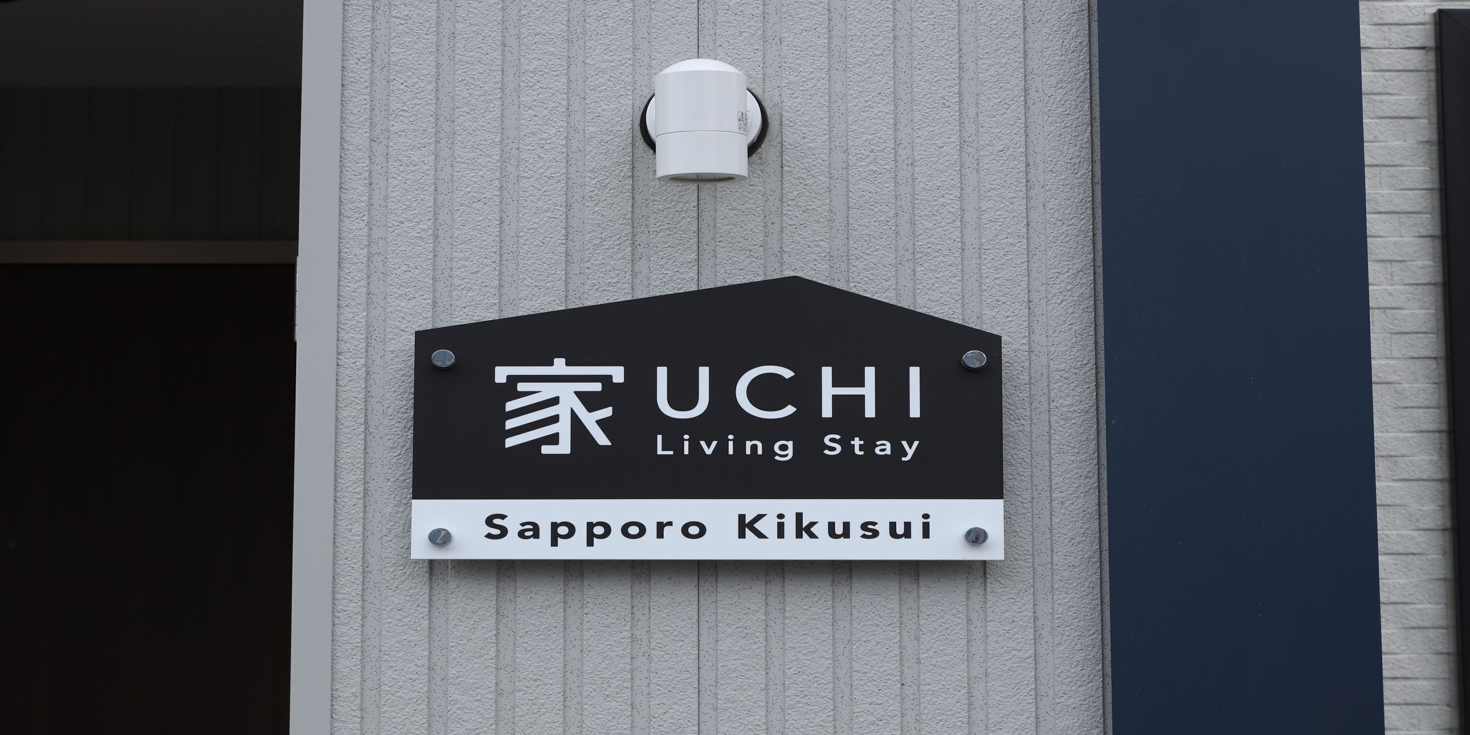 Letrero de UCHI Living Stay en Sapporo Kikusui, con un diseño moderno que incluye un logotipo y el nombre.