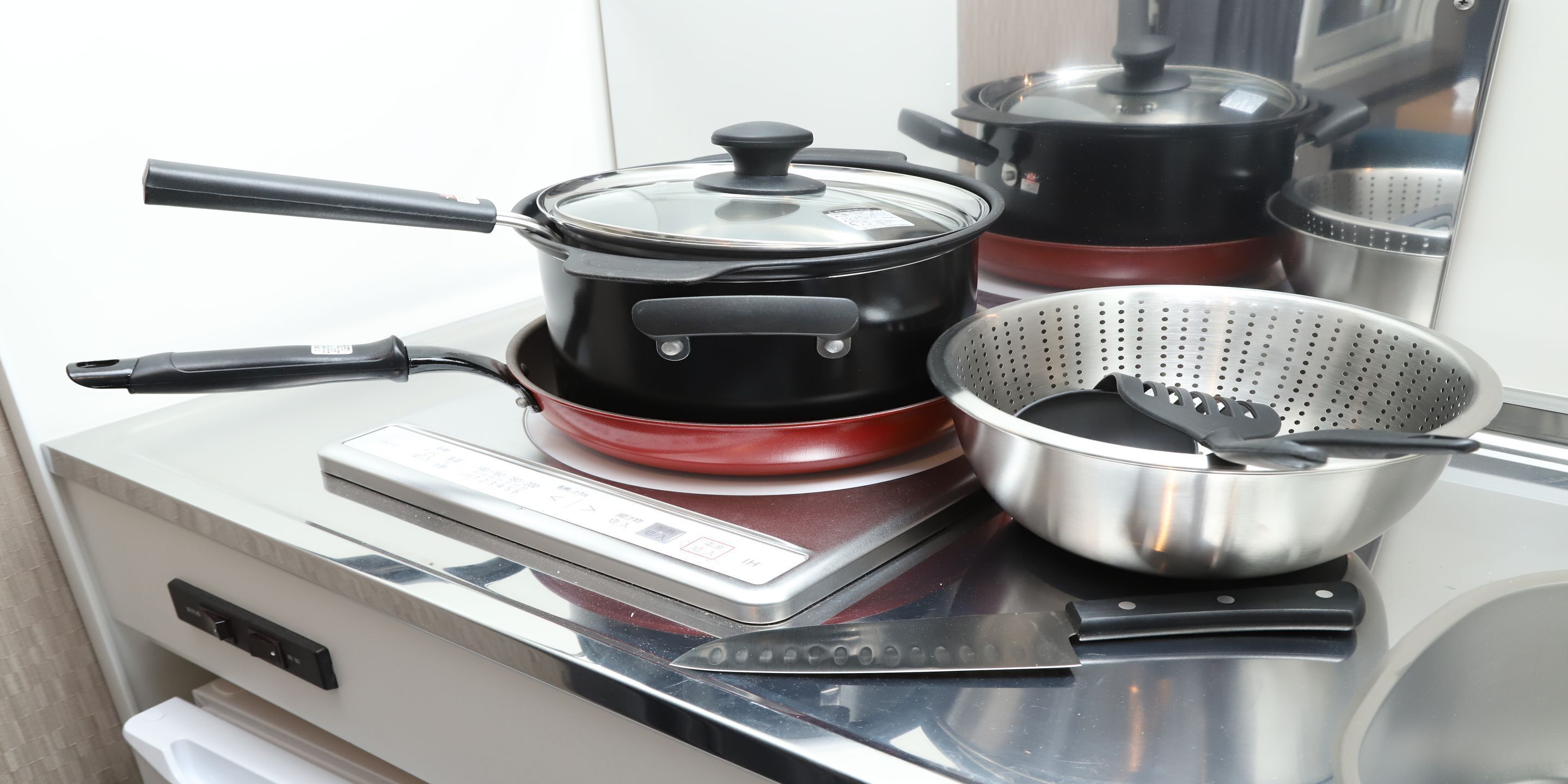 A kitchen with a stove, pots, and a colander.