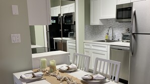 Une cuisine moderne avec des meubles blancs, un four à micro-ondes encastré et un réfrigérateur en acier inoxydable.