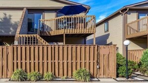 Un immeuble résidentiel de deux étages doté d’une terrasse en bois et d’un balcon.
