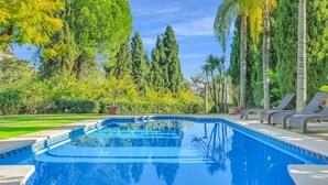 Ein Swimmingpool mit Liegestühlen und Palmen im Hintergrund.