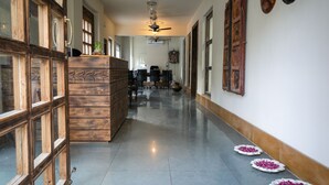 Un couloir avec un comptoir d’accueil en bois, des chaises de bureau et un ventilateur de plafond.