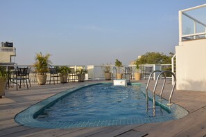 A rooftop pool with a clear blue water feature, surrounded by potted plants and outdoor furniture. - Hotel Shambhu Villas (Udaipur)